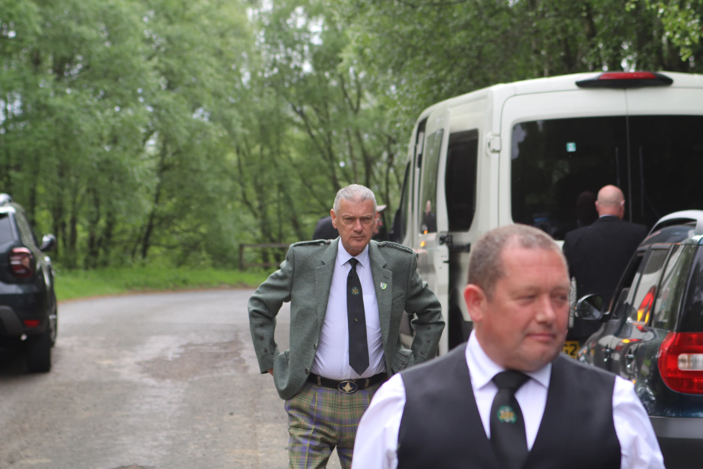 Lodge members wearing Masonic ties beside a minibus on a wooded driveway